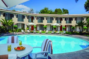 Ein Poolbereich mit Tisch, Stühlen und einem Esstisch mit Speisen und Getränken.