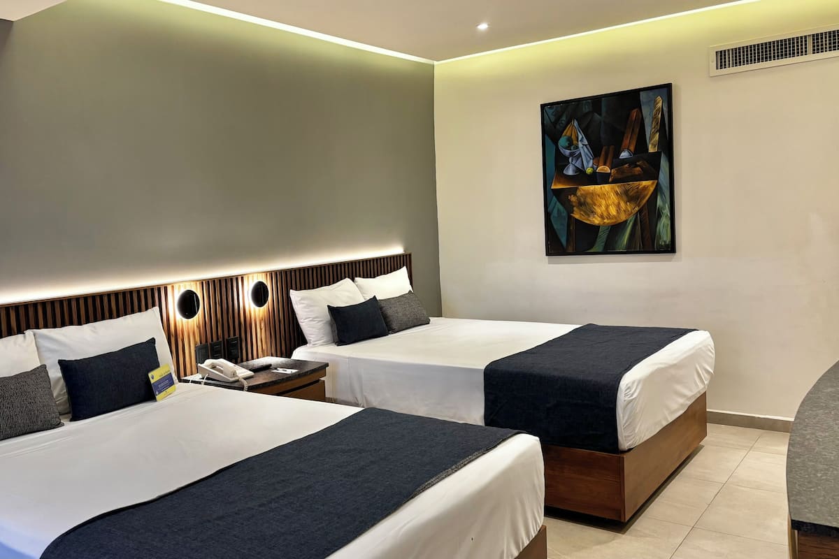 Une chambre d’hôtel avec deux lits, une table de chevet avec un téléphone, un tableau au mur et un design moderne.