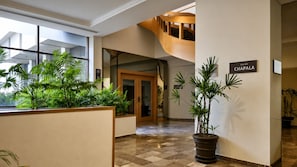Un vestíbulo de hotel con piso a cuadros, una escalera y plantas en macetas.