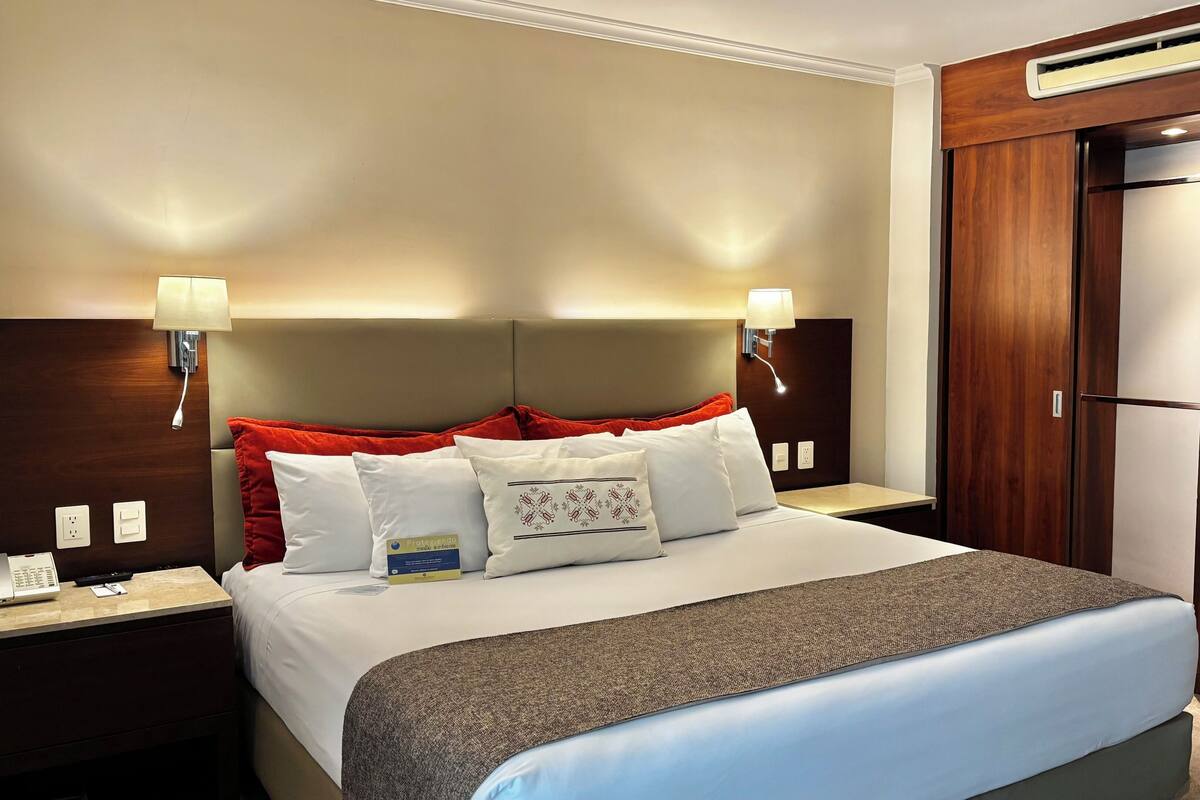 Une chambre d’hôtel équipée d’un lit, de tables de chevet, d’un bureau, d’une armoire et d’un appareil de climatisation.