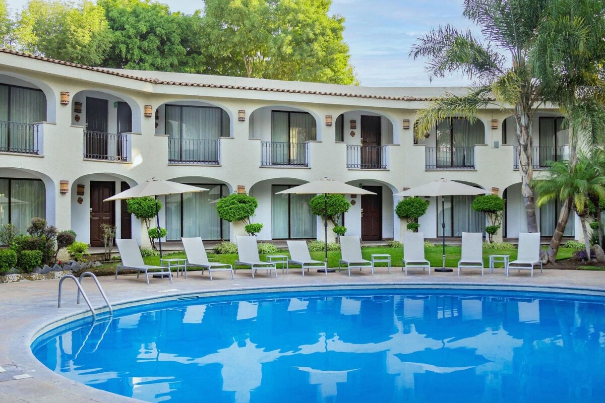 A hotel with a swimming pool, multiple balconies, and outdoor seating.