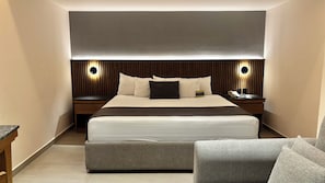 Une chambre dâhĂŽtel moderne avec un grand lit, des tables de chevet avec des lampes et un coin salon.