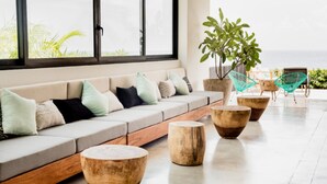 Un espacio moderno para relajarse con sofá, taburetes de madera y vista al océano.