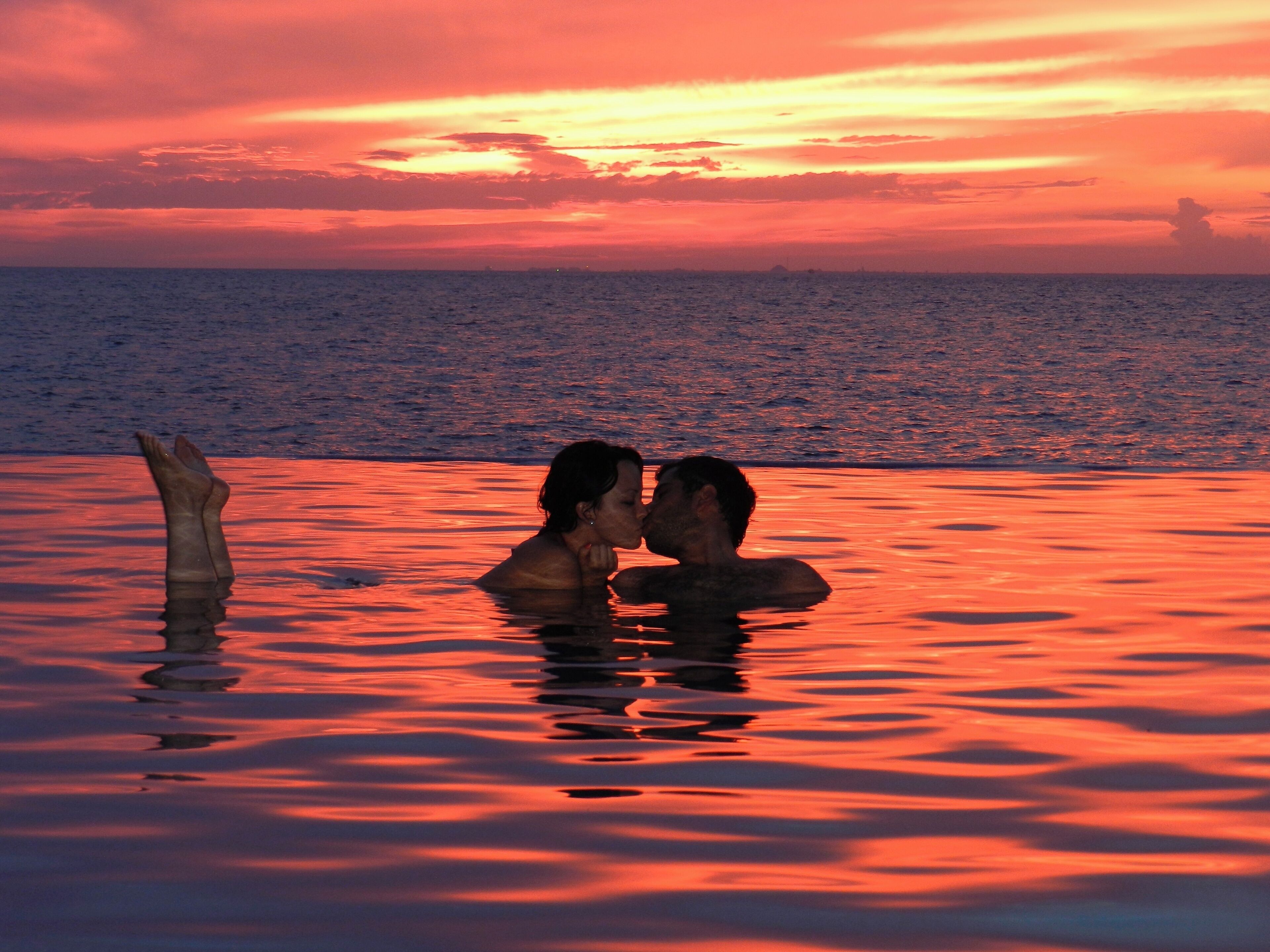 Un atardecer sobre un cuerpo de agua con dos personas en primer plano.