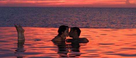 Un atardecer sobre un cuerpo de agua con dos personas en primer plano.