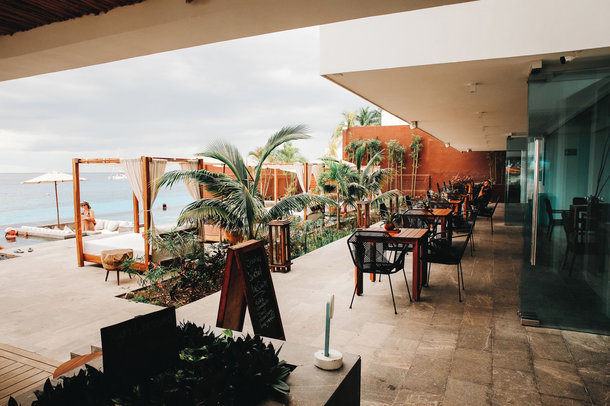 Una terraza con asientos al aire libre, piscina y vista al océano.