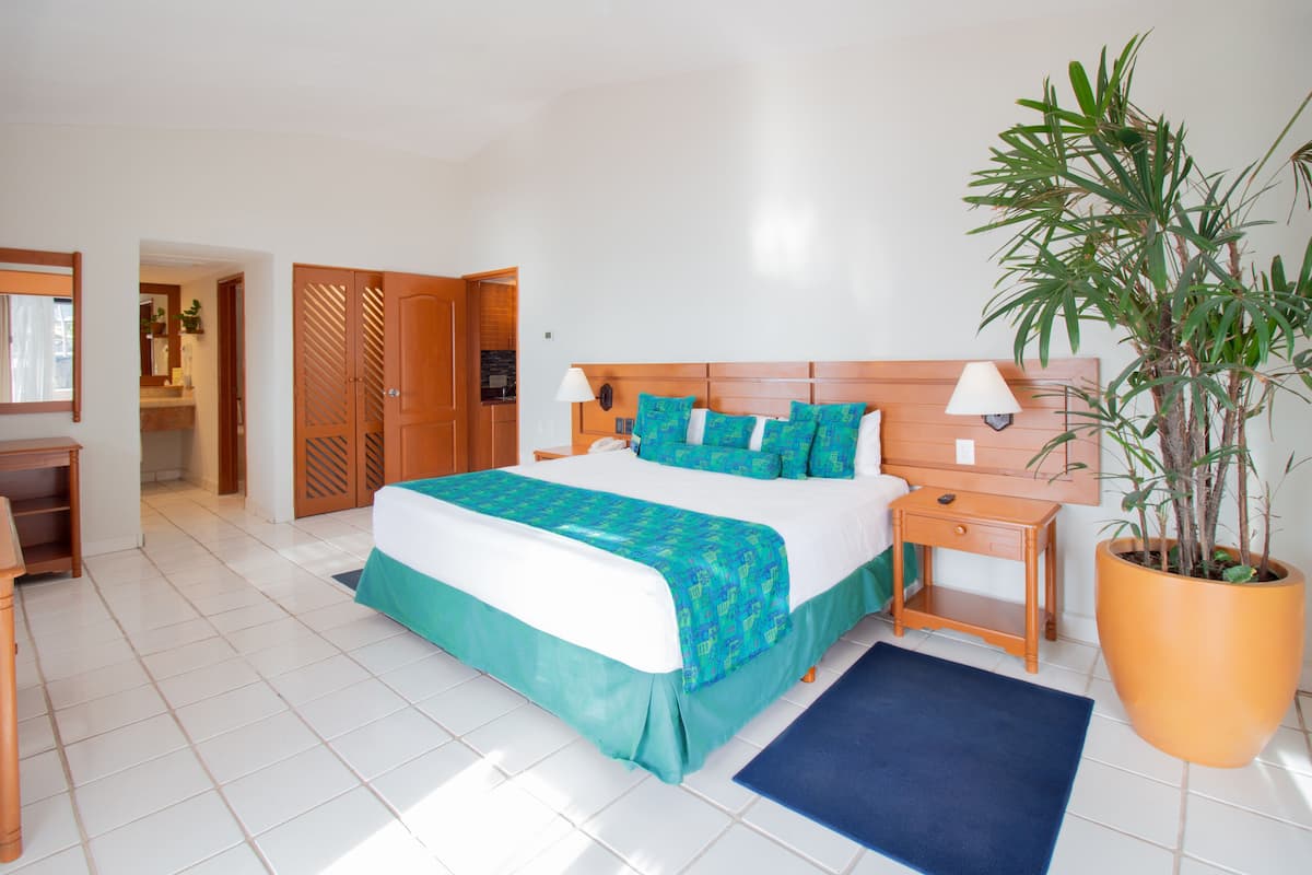 Une chambre à coucher avec un lit, des tables de chevet, une petite table, une plante en pot et un tapis bleu.