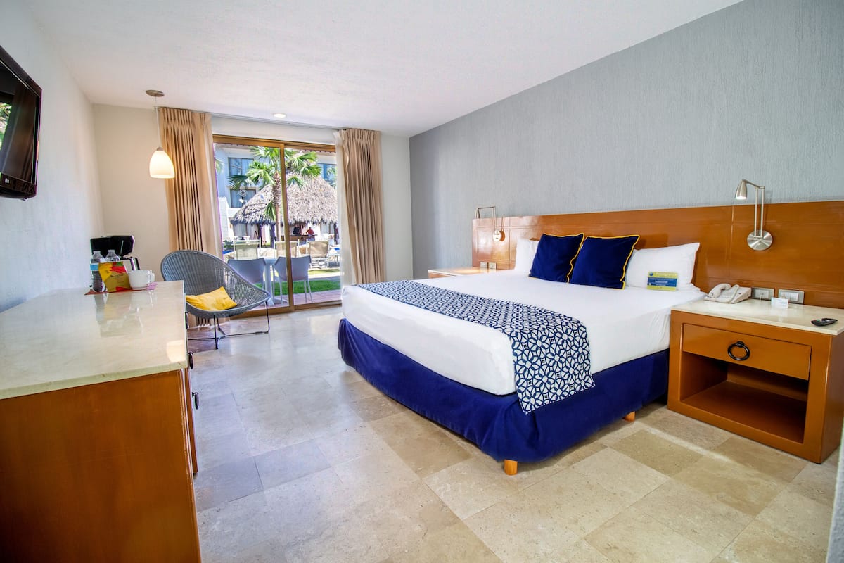 Une chambre d’hôtel comprenant un lit, une table de chevet et un bureau avec une chaise.