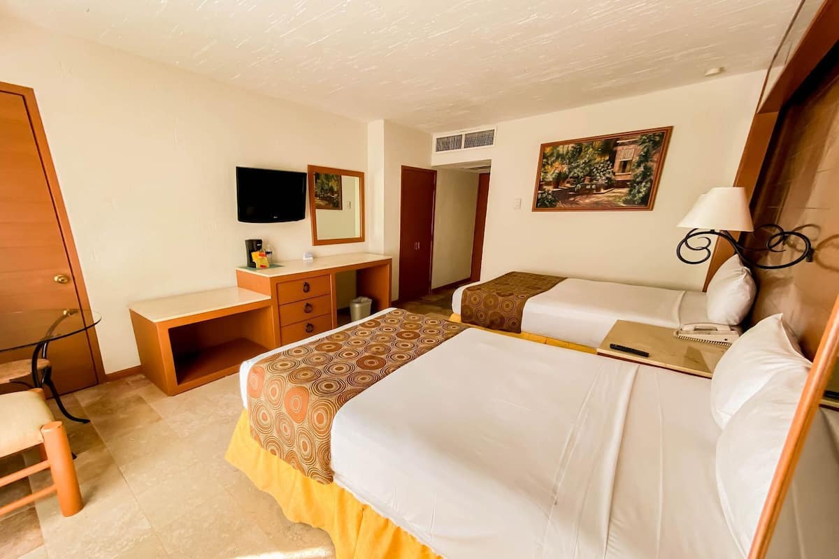 Une chambre d’hôtel avec un lit, un bureau, une chaise, une télévision et un tableau au mur.