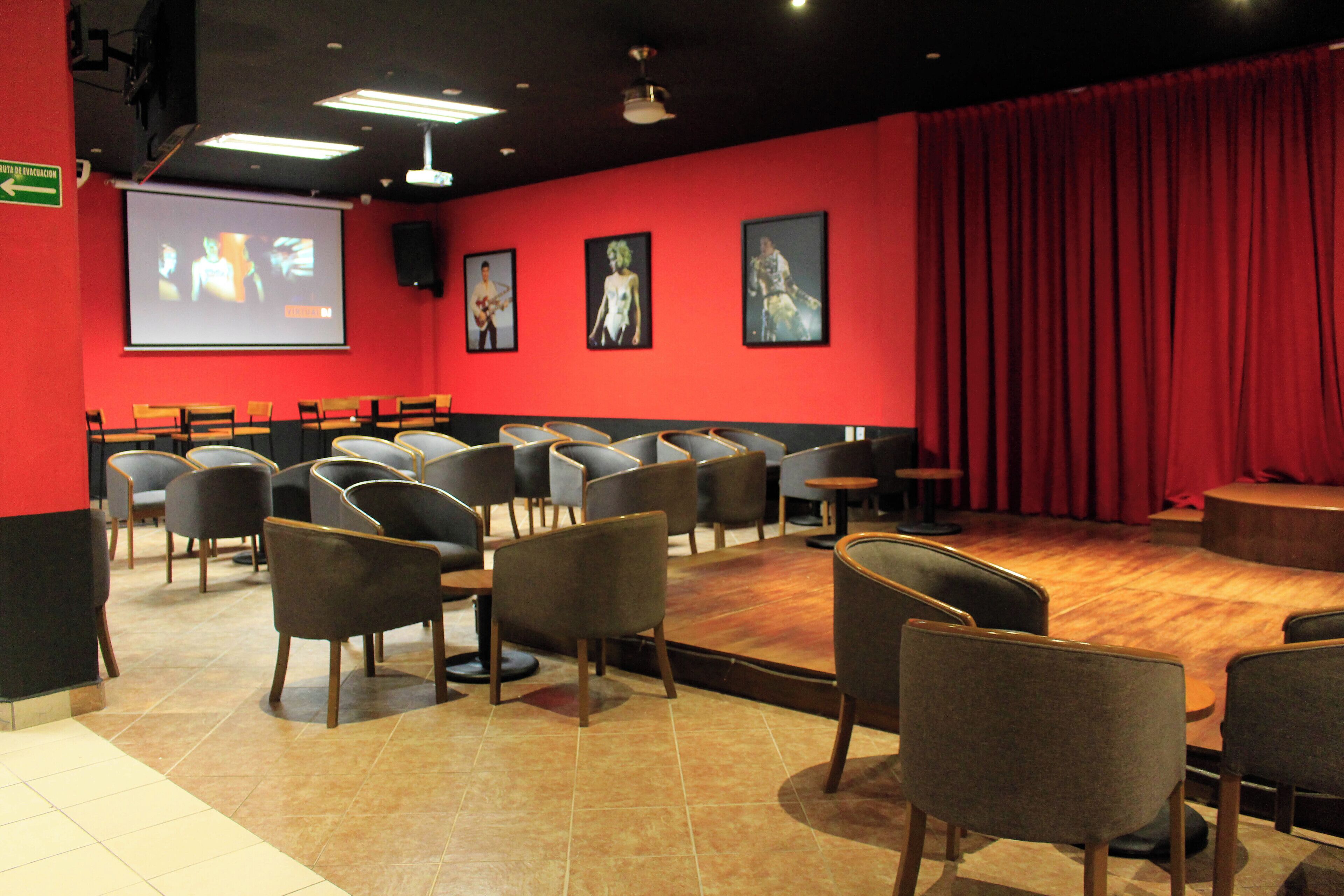 A theater with rows of seats, a stage, and a screen displaying a presentation.