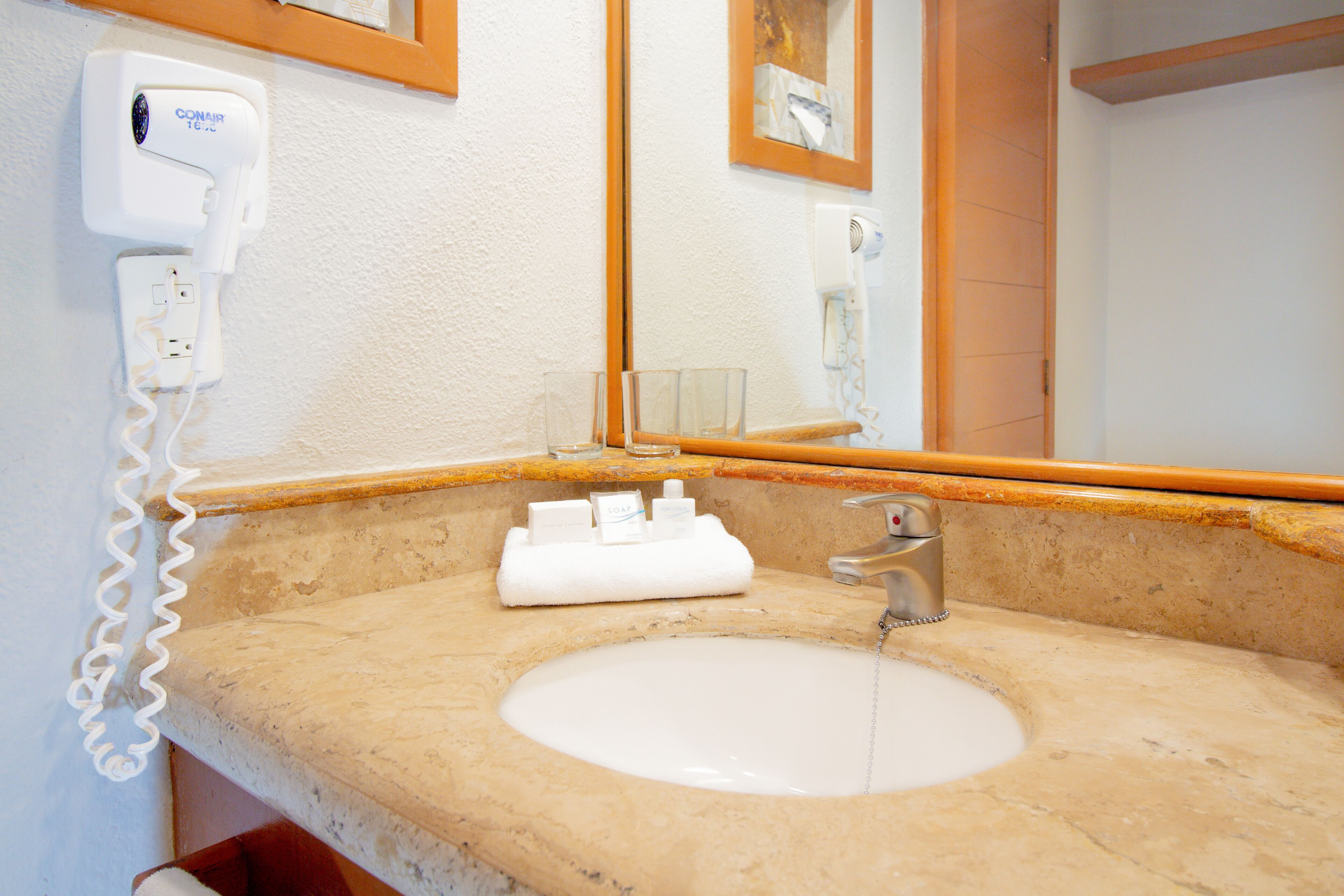 A bathroom with a sink, a mirror, a hairdryer, and a towel rack.