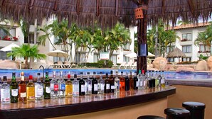 Un espace bar avec vue sur la piscine, entouré de chaises longues et de parasols, le tout dans un cadre évoquant un complexe hôtelier tropical.