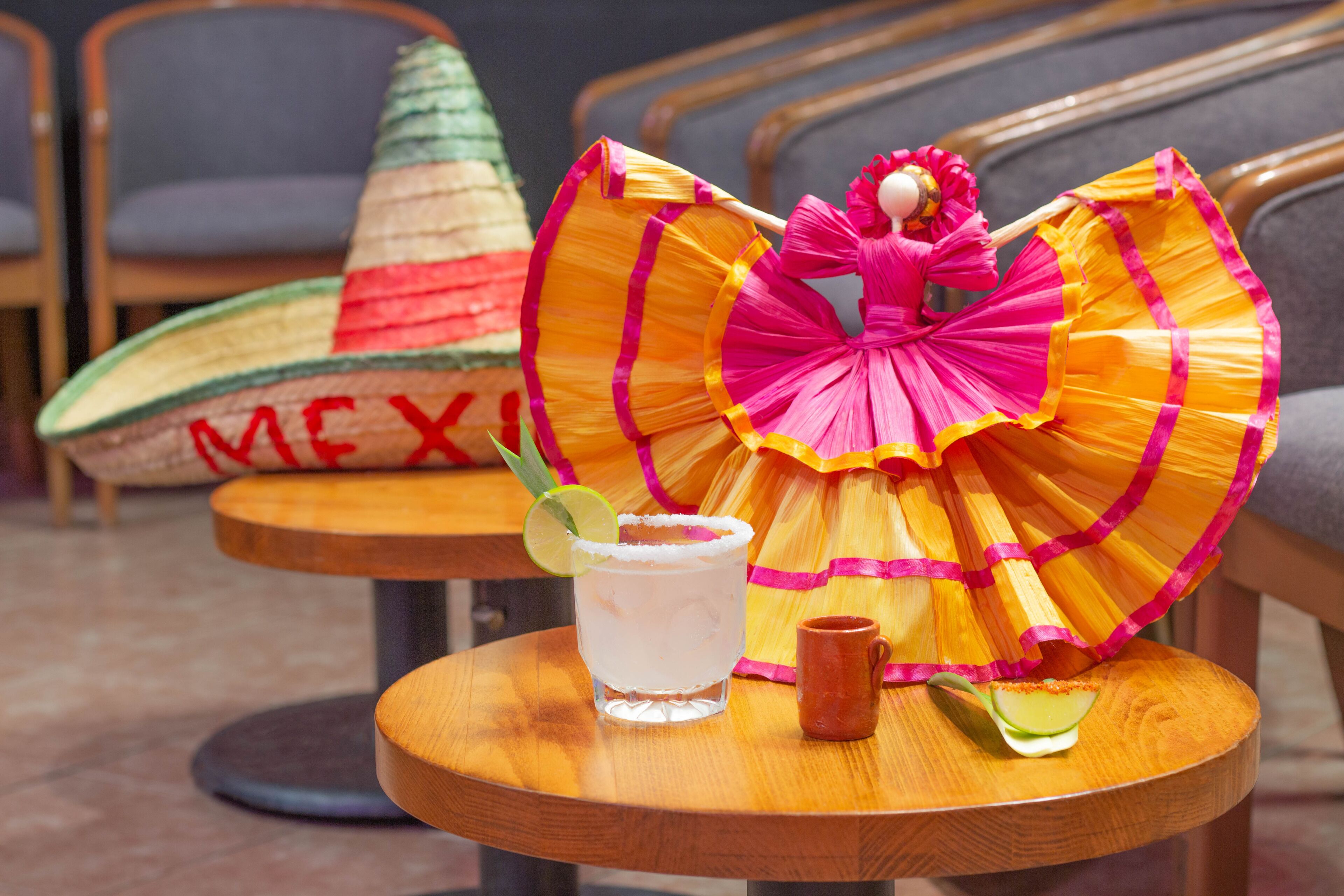 Una mesa con una bebida, una taza pequeña y un adorno.
