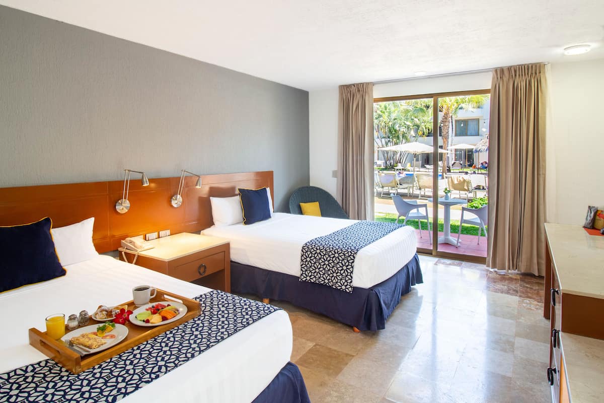 Une chambre d’hôtel avec deux lits, un bureau et un balcon doté d’un espace salon extérieur.