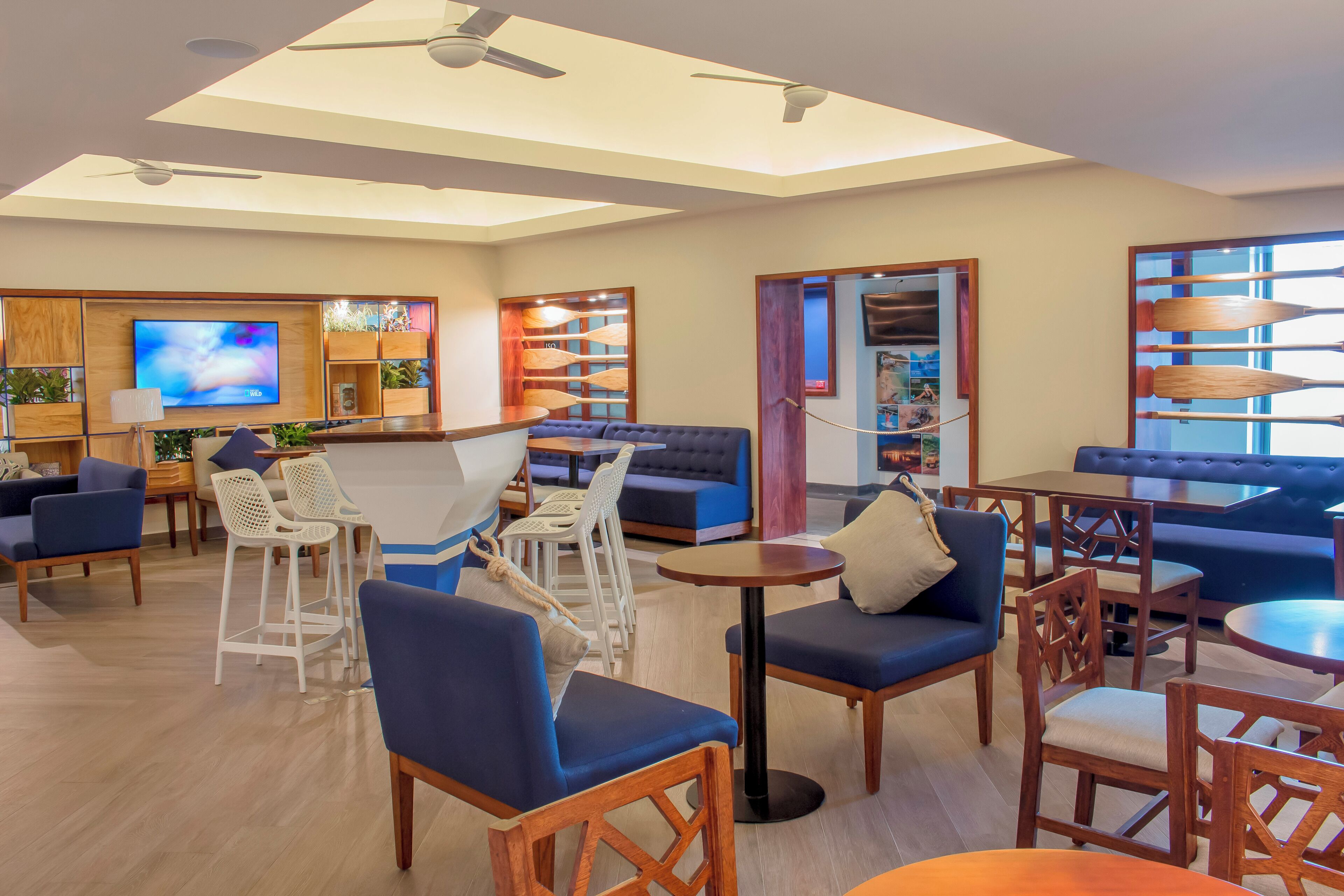 Un moderno vestíbulo de hotel con zonas de estar, un bar y una pantalla de televisión.