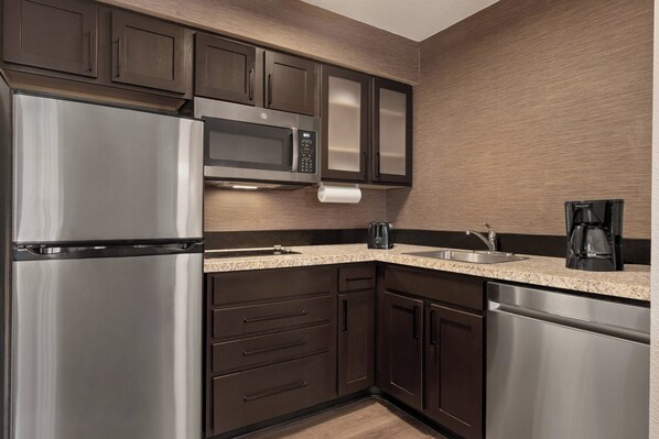 A modern kitchen with stainless steel appliances, dark wooden cabinets, and a granite countertop.