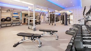 Ein modernes Fitnessstudio mit unterschiedlichen Trainingsgeräten, darunter Laufbänder, Kurzhanteln und Kraftgeräte.