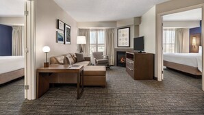 Ein Hotelzimmer mit Bett, Sofa, Schreibtisch, Fernseher und Kamin.
