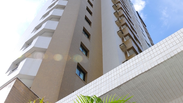 Un immeuble imposant, doté d’une architecture moderne, avec une série de balcons et une façade ornée de motifs.