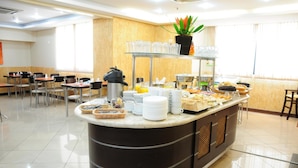 Un buffet proposant une variété de plats et d’ustensiles, un coin café et une plante en pot.