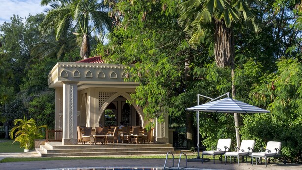 A pool area with lounge chairs and a covered seating area surrounded by lush greenery. - Dar Es Salaam Serena Hotel (Dar es Salaam)