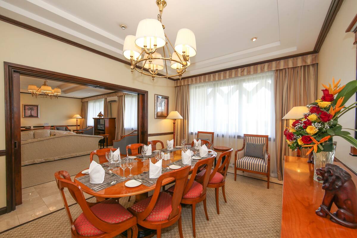 A dining area with a wooden table set for six, surrounded by red cushioned chairs.