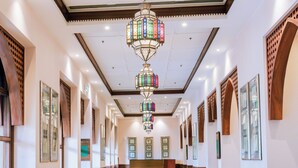 A spacious hallway with a decorative hanging chandelier, wooden paneling, and framed artwork on the walls. - Dar Es Salaam Serena Hotel (Dar es Salaam)