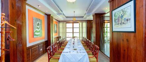 A long dining table set with chairs, a chandelier, and artwork on the walls.