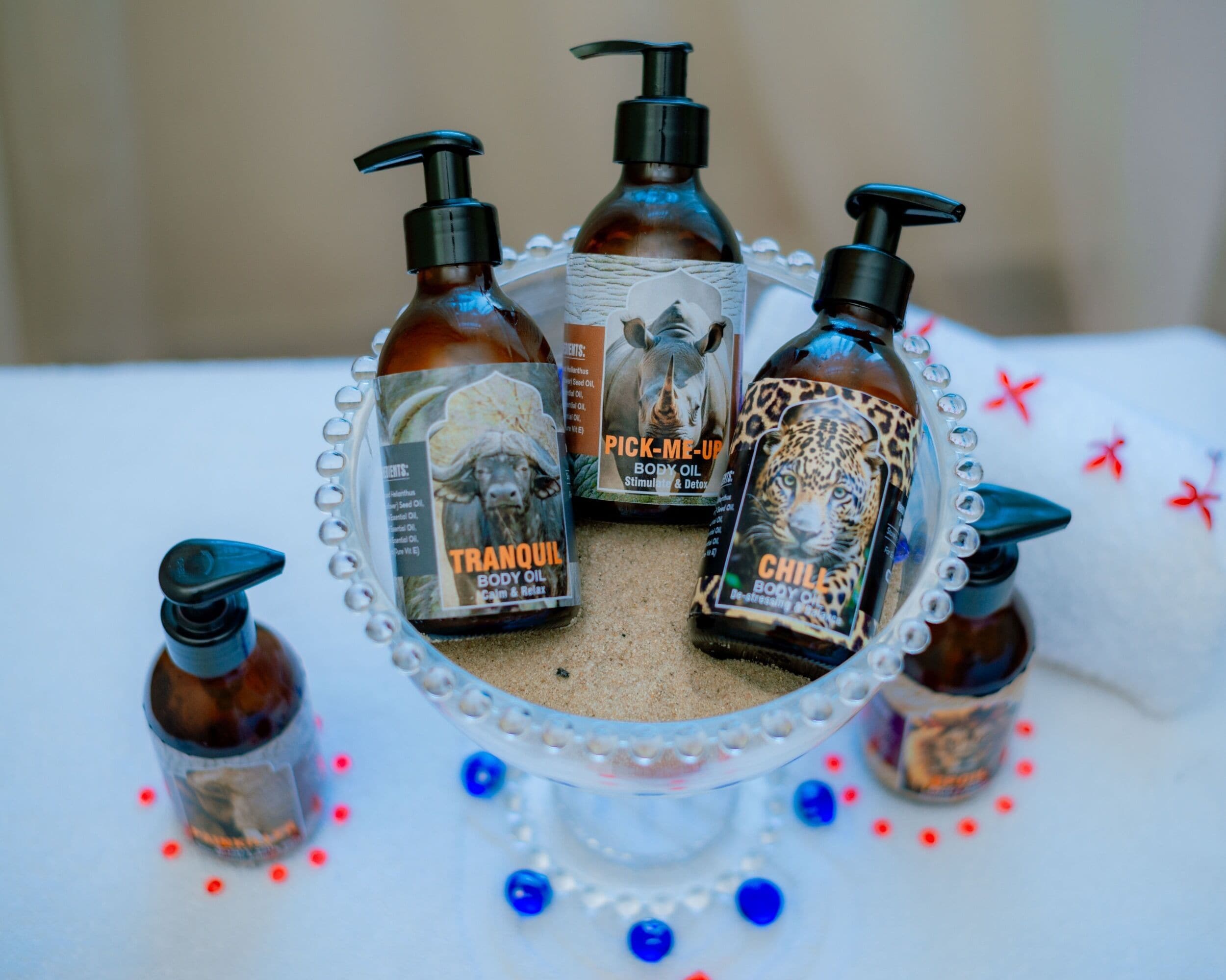 A table with three bottles of body oil and one smaller bottle, surrounded by decorative beads.