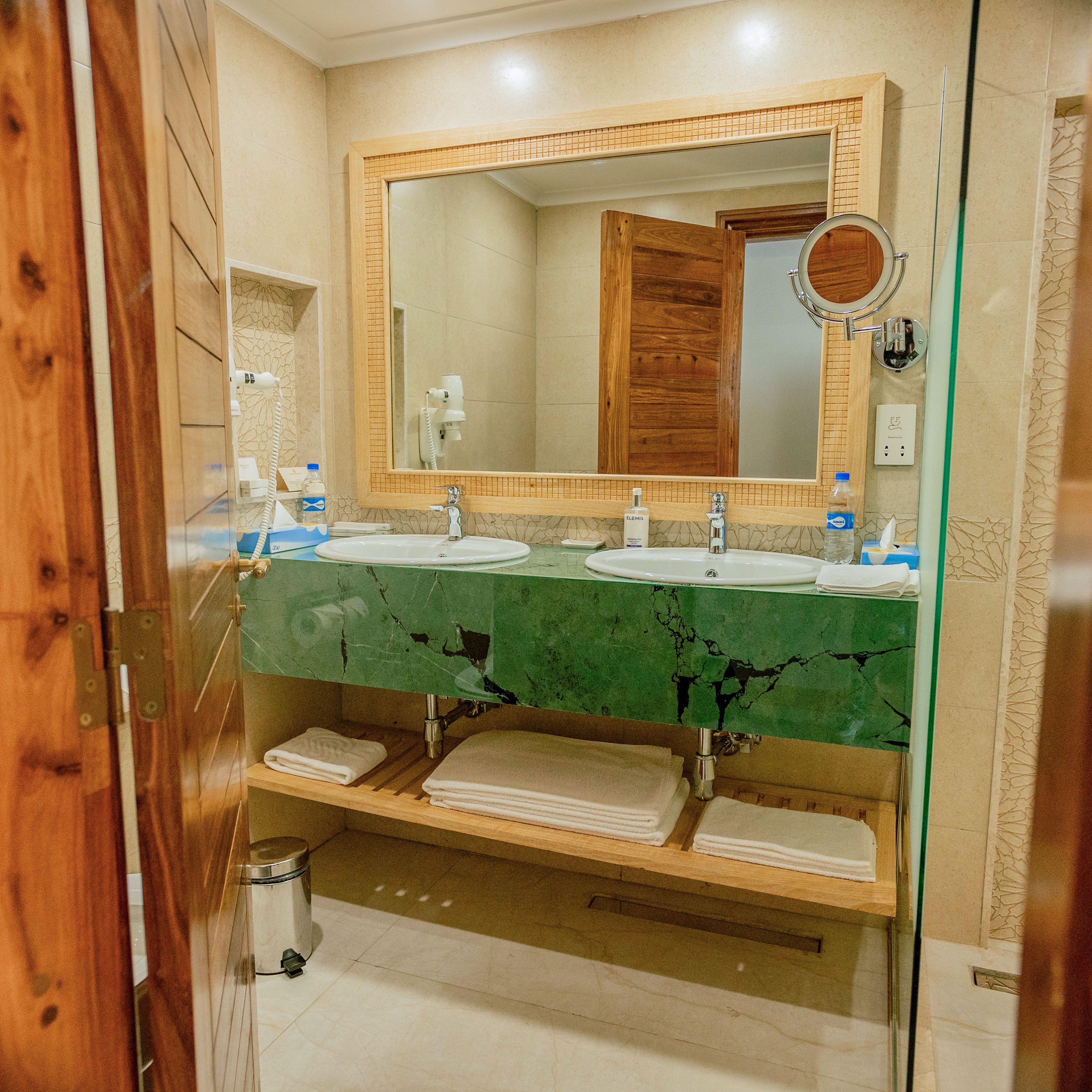 A bathroom with two sinks, a large mirror, and a wooden vanity.