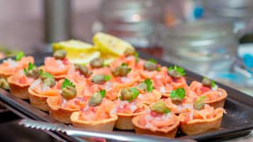 Uma bandeja de aperitivos com tartare de salmão, alcaparras e salsa, acompanhada de gomos de limão.