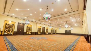 Un salón amplio con alfombras ricamente decoradas, candelabros y puertas ornamentales.