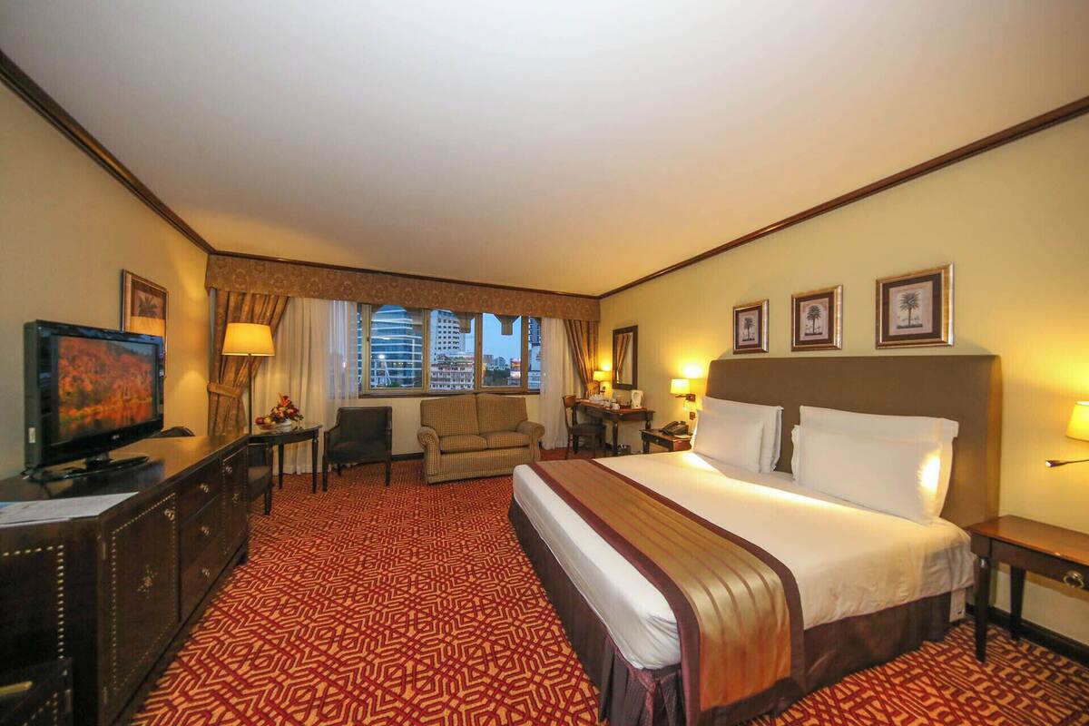 A hotel room with a large bed, a desk with a computer, a chair, and a television.