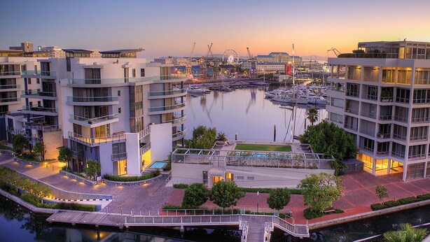 A marina with boats, modern buildings, and a sunset. - Waterfront Village (Cape Town)