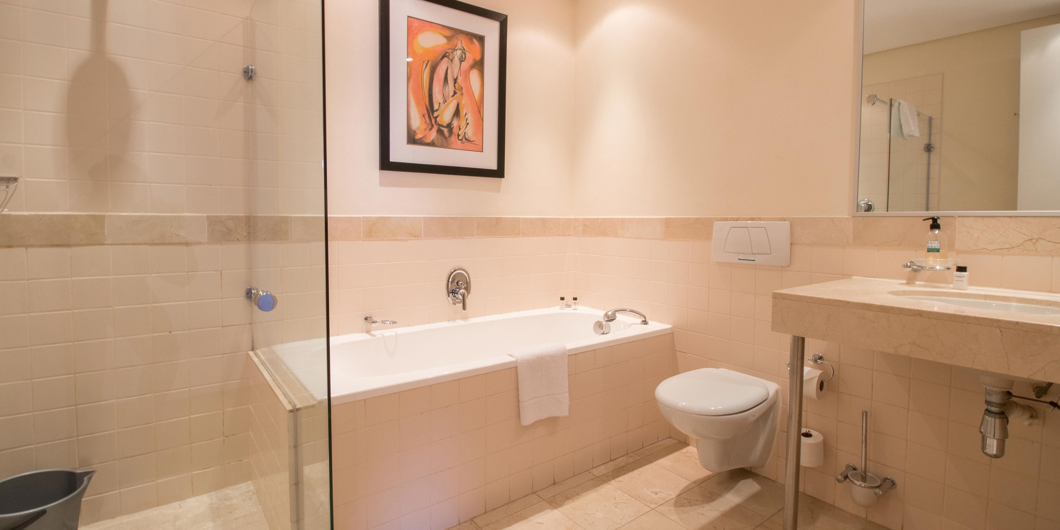 A modern bathroom with a glass shower enclosure, a bathtub, a toilet, and a sink.