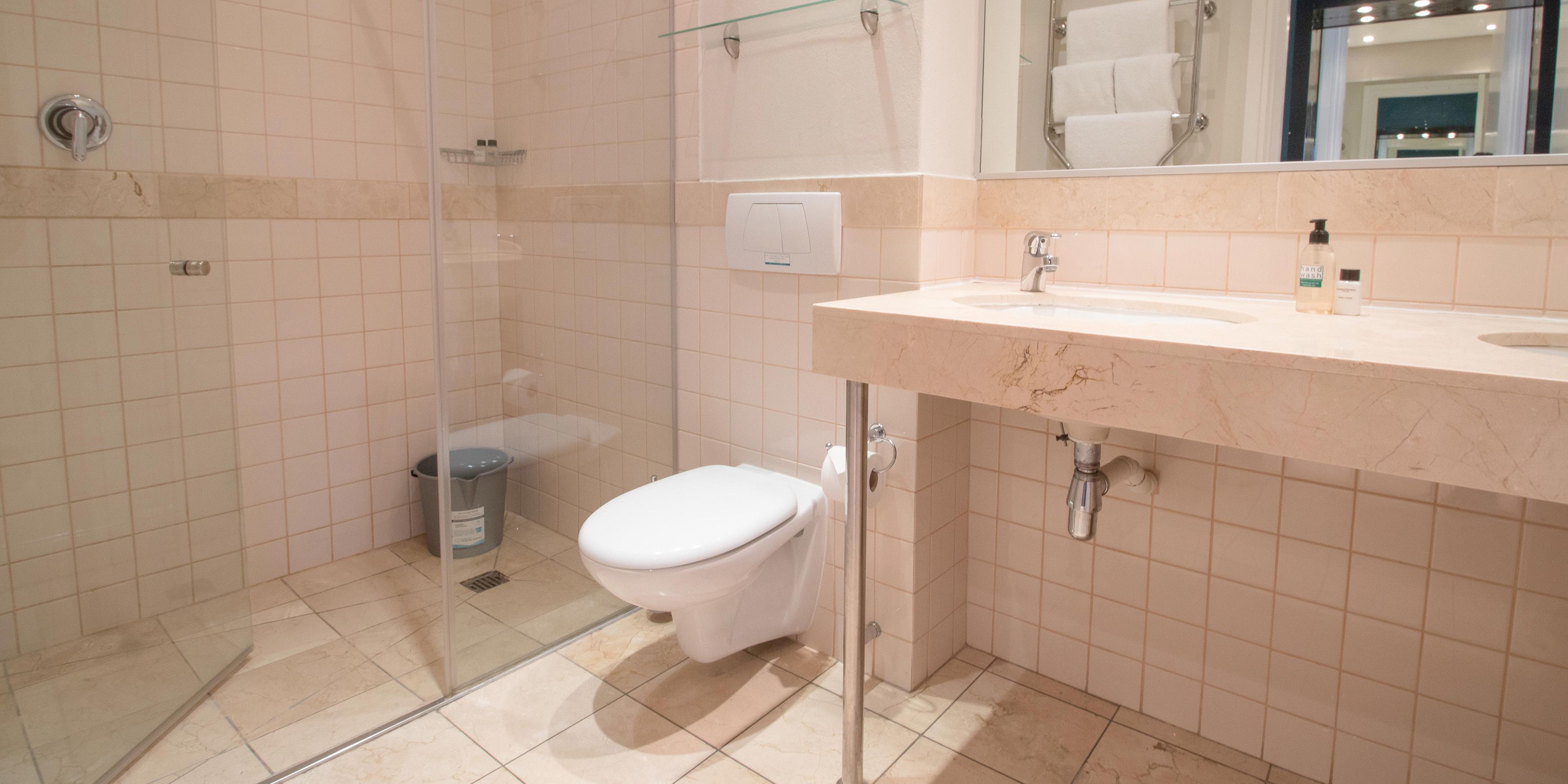 A modern bathroom with a glass-enclosed shower, a toilet, and a sink with a marble countertop.
