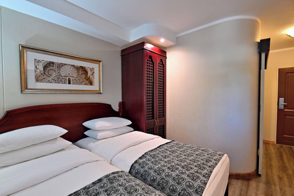Une chambre d’hôtel avec un lit, une armoire, un tableau encadré au mur et une porte.