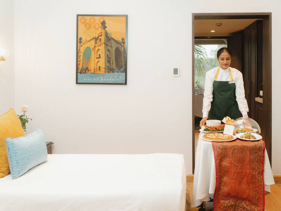 A hotel room with a bed, a table with a tablecloth, and a wall with a framed picture.