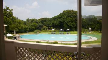 Relax by the oval-shaped pool surrounded by lush greenery and lounge chairs.