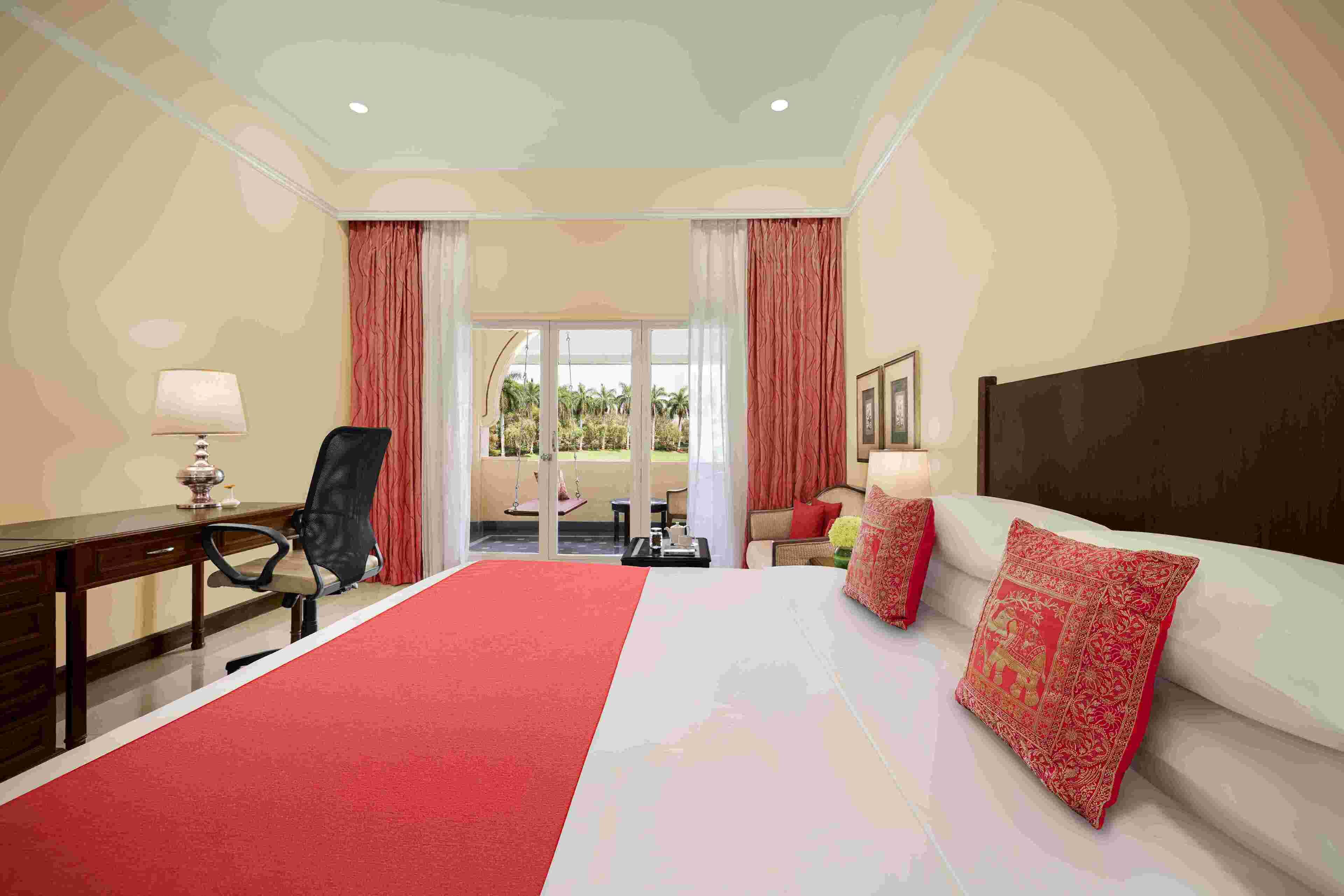 A hotel room with a large bed, a desk with a chair, a sofa, and a view of the outdoors.