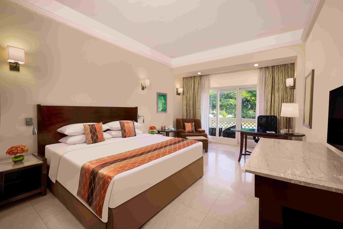Een hotelkamer met een groot bed, een bureau, een stoel en uitzicht op de omgeving.
