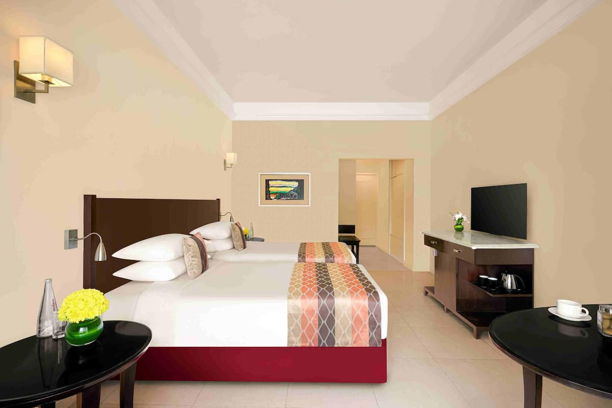 Een hotelkamer met een bed, televisie, bijzettafeltje en bureau.
