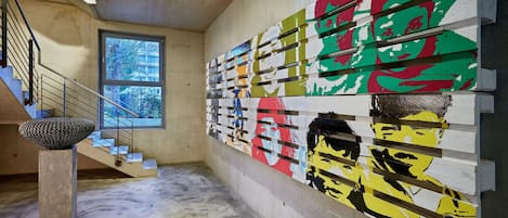 A modern interior with a concrete staircase, a large window, and a colorful mural on the wall.