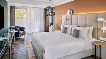 Ein modernes Hotelzimmer mit einem großen Bett, einem Schreibtisch, einem Sessel und einem Fernseher.