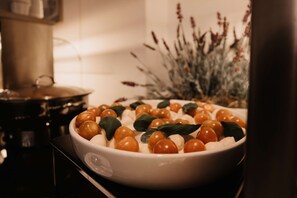 A white bowl filled with cherry tomatoes and basil leaves on a kitchen counter. - Tulip Inn Ludwigshafen City (Ludwigshafen)