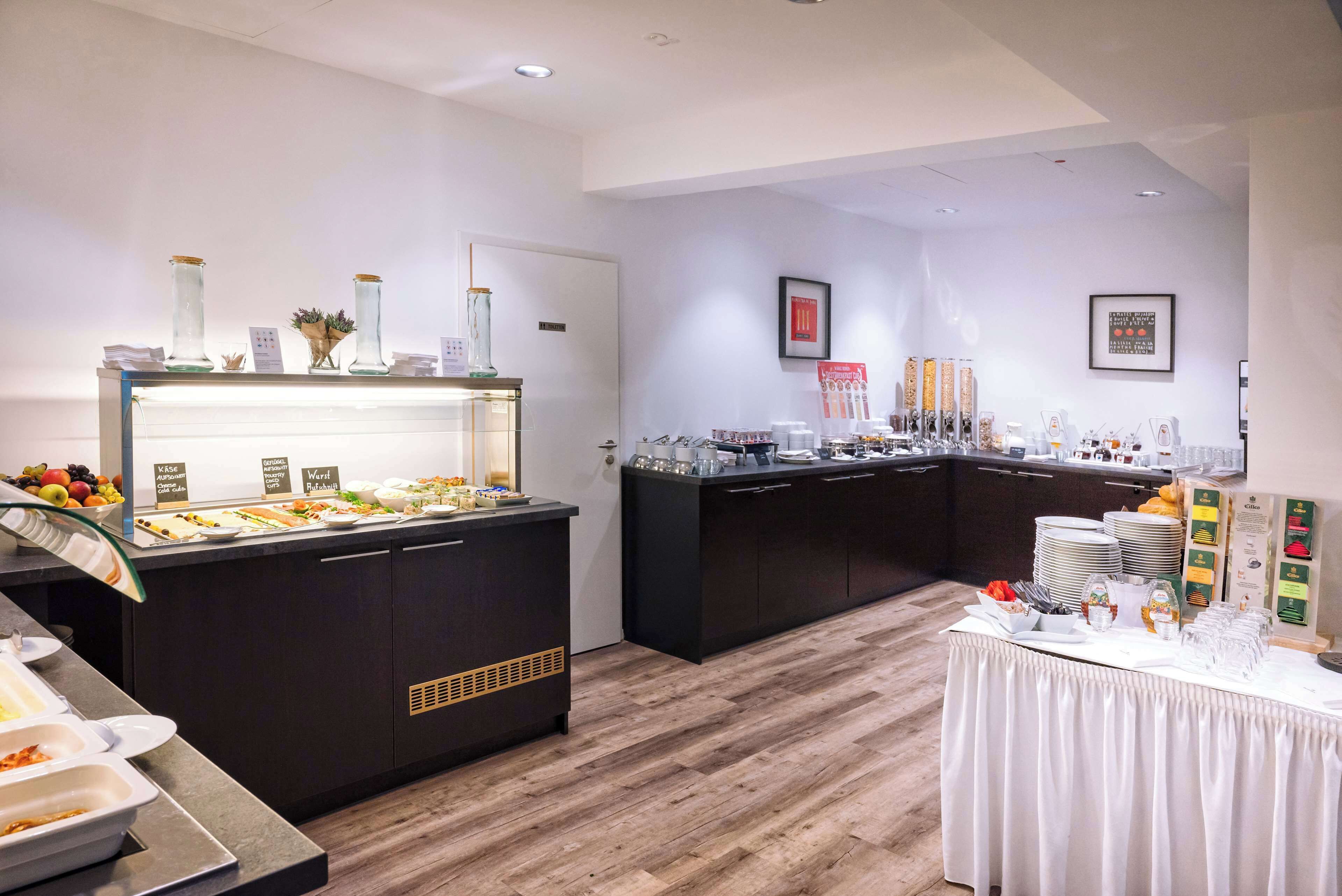 Zona de buffet con diferentes estaciones de comida, que incluyen una presentación de frutas y una estación de bebidas.