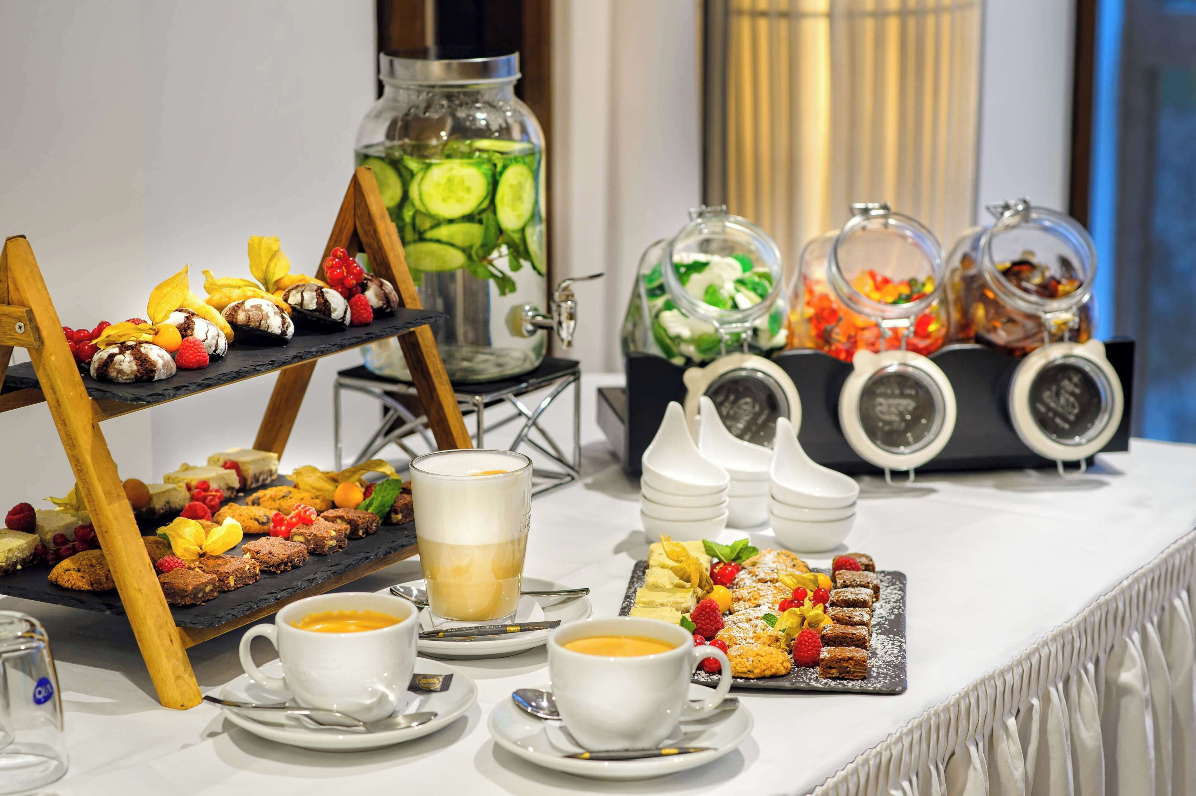 A buffet table with various food items, including pastries, fruits, and beverages.