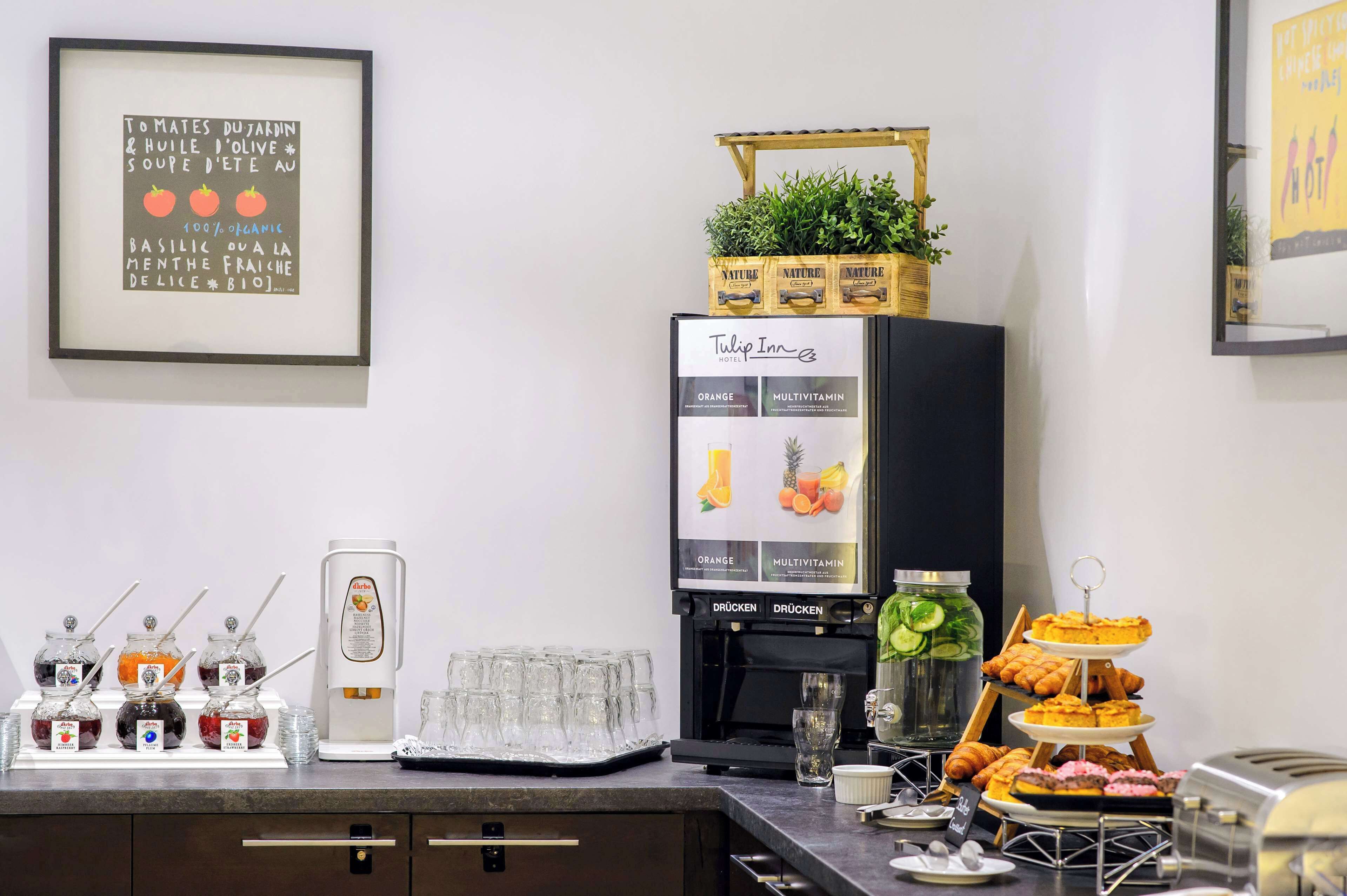 A buffet setup with various food items, a coffee machine, and a refrigerator with a sign.
