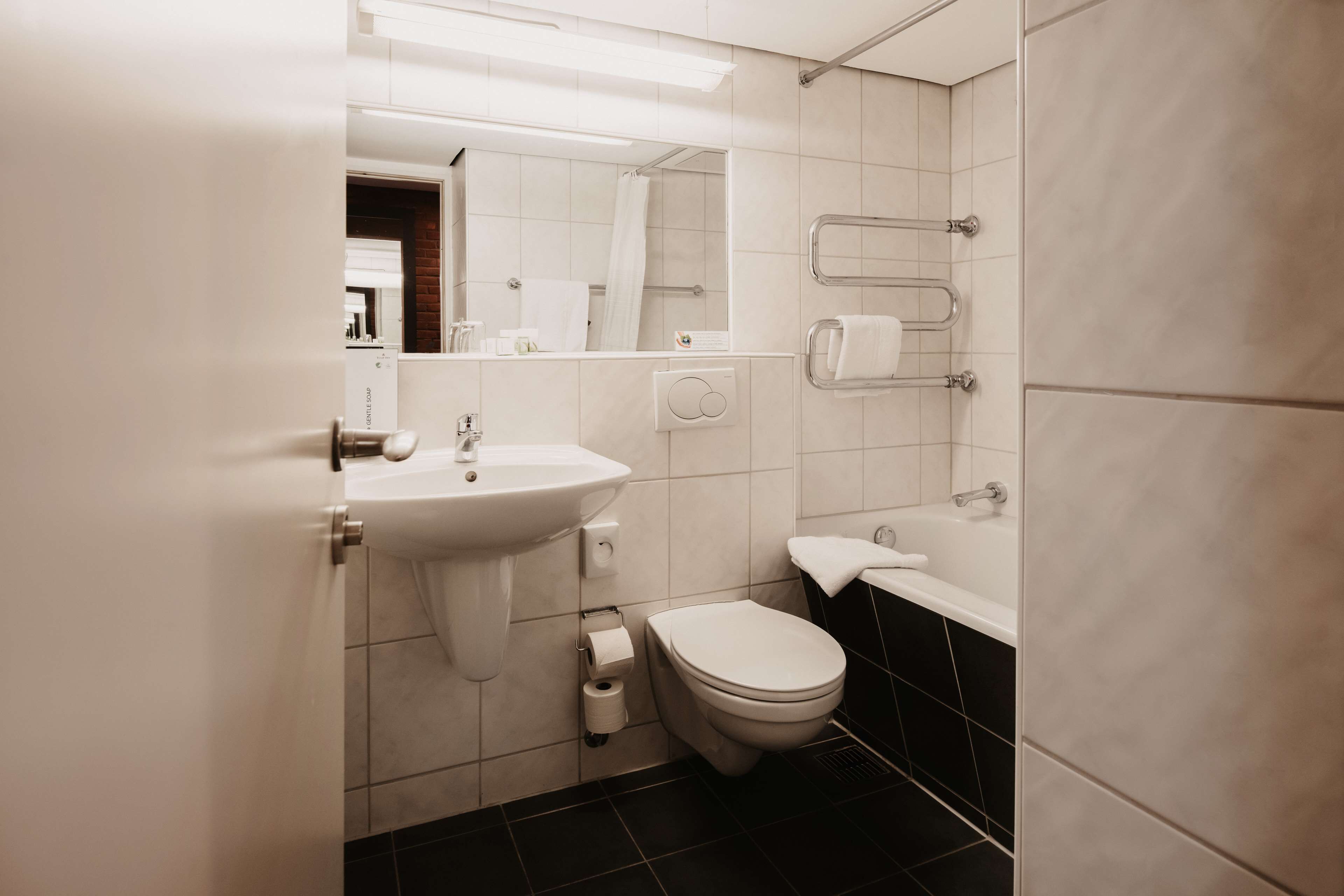 A modern bathroom with a sink, toilet, and bathtub.