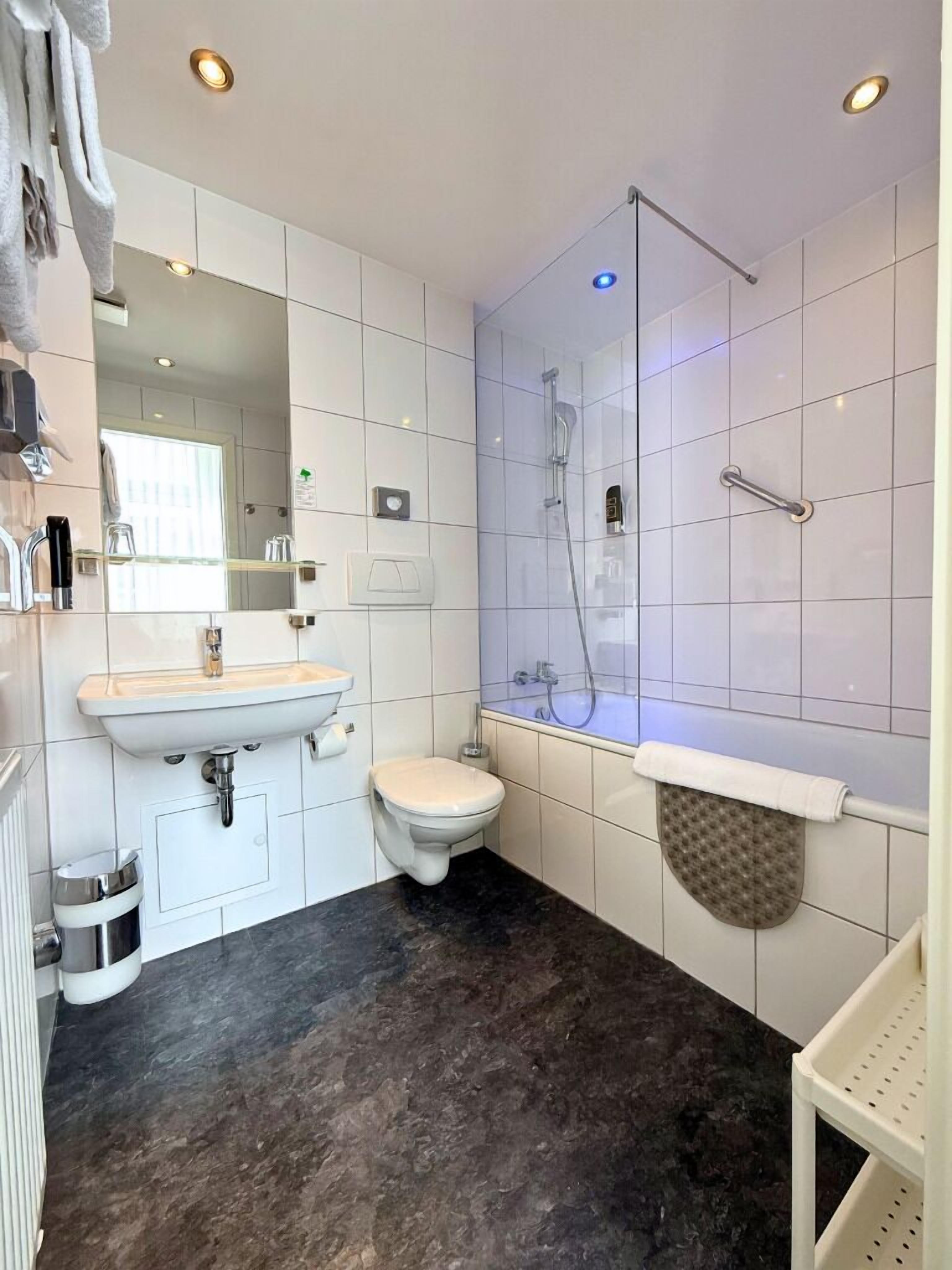 A modern bathroom with a sink, toilet, and shower.